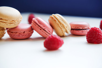 Close-up photo. Colorful French macarons with raspberries on a table