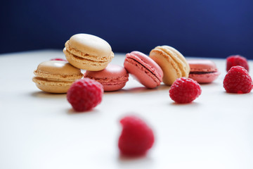 Close-up photo. Colorful French macarons with raspberries on a table
