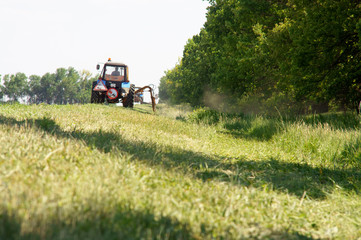 Tractors machines mowing lawn grass along road