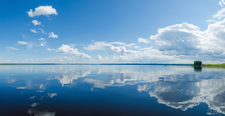 Panorama of calm lake, Kama river blue sky with clouds reflected in the water. - 253378068