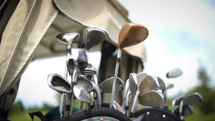 Close up of a bunch of golf clubs in the back of a cart.