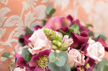 wedding bouquet with pink and purple flowers, 2 gold wedding rings on flowers