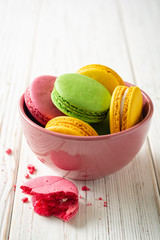 Colorful french macarons in bowl on white wooden background. Selective focus.