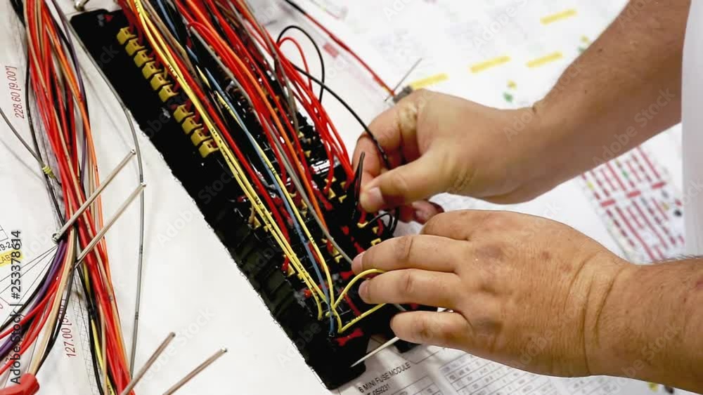 Poster the hands of a worker assembling wires on a testbed at a stock-wire factory. close-up shot.