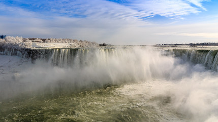 Niagara Falls on the Canadian US border in winter.  Coulds of frozen spray in the air.