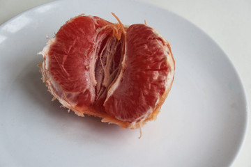 Half a grapefruit on a white plate. Candid.