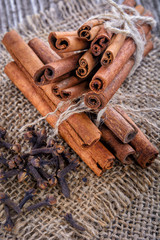 Fragrant spices – cinnamon and cloves on sackcloth on rustic wooden table - Image