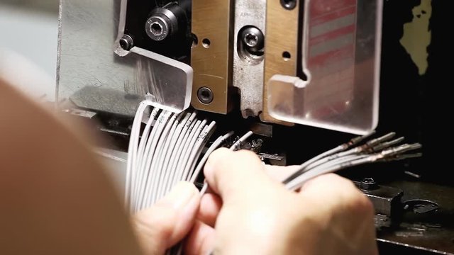At a stock-wire factory: a worker putting wire ends under a terminating machine.