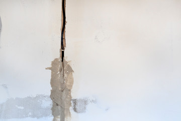 technical hole in it is an electrical wire. the wall is white. Master with a spatula and mortar covers the cable