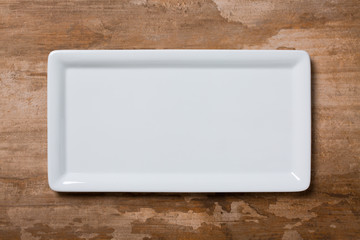 Empty white plate on brown wooden background