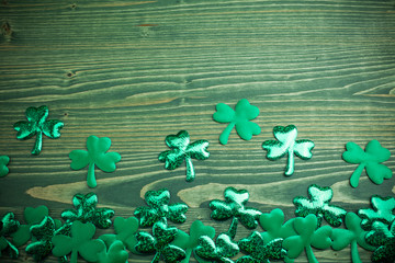 Glittery shamrocks on a wooden green background with space