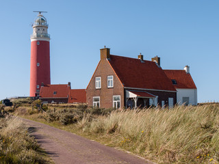 red lighthouse with house on a dune with grass at the North Sea on the island Texel, Netherlands