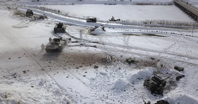 Tanks, armoured vehicles in snow-covered fields, soldiers fighting, shooting, explosions during an Afghanistan battle reconstruction near Minsk, Belarus