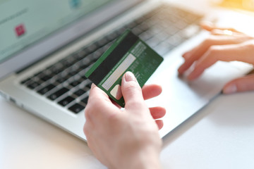 Woman holding in hand a credit card,while is doing shopping online.