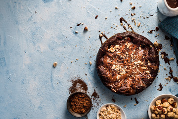Chocolate cake with hazelnuts on a blue textured background and a copy space