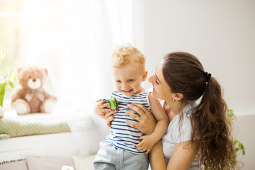 Young mother kissing her baby lying on the bed
