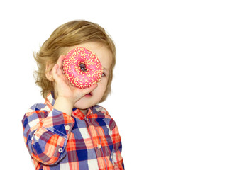 Little happy cute boy is eating donut on white background wall. Child is having fun with donut. Tasty food for playing kids. Funny time  with sweet food. Bright baby boy in a plaid shirt.