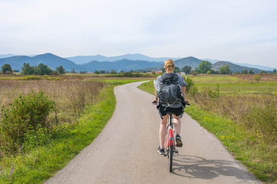 woman riding the bike through the fields in central croatia