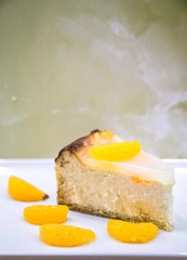 Evening table and sweet concept . Birthday Party Piece of Homemade Cheescake with Tangerines on white Plate