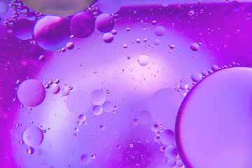 Abstract background with purple color. Distortions in water with drops of oil. Bright abstraction, ultraviolet. Circles on the water