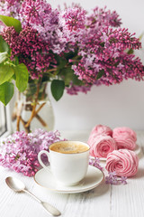 Bouquet of lilacs, cup of coffee, homemade marshmallow and stack of books on window sill Romantic spring morning.
