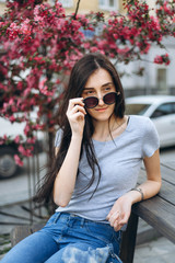 Young attractive brunette woman sitting outside in sunglasses