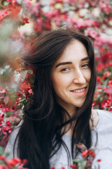 Goergous attractive young smiling woman in the middle of the pink flowers