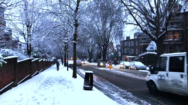 Snowy London city scene person walking down street past traffic