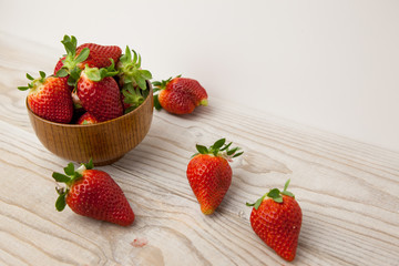 Fresas en un bol y sobre la mesa