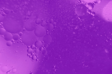 Abstract background with purple color. Distortions in water with drops of oil. Bright abstraction, ultraviolet. Circles on the water