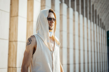 Attractive athletic man practicing yoga with maces outdoors in modern park.