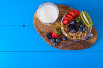 muesli with berries and fruits on blue wooden background