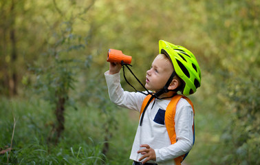 The little boy young researcher exploring with binoculars and backpack environment