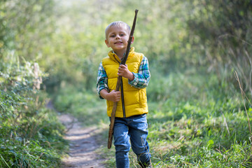 Naklejka na ściany i meble Young boy with a stick alone exploring the area