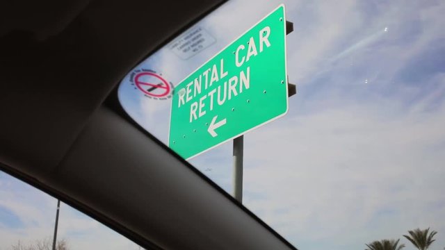 Driving by a car rental return sign at the airport in america