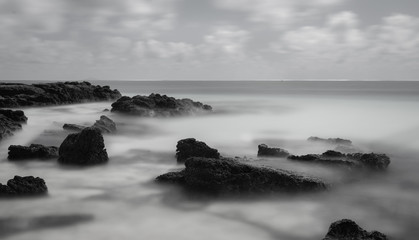 Fototapeta na wymiar Rocks in water at beach long exposure