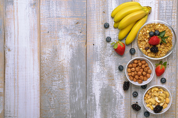 muesli with fruit, berries, nuts on wooden background