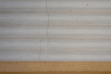 Graue Wand mit rauen Wellen und Rissen in der Wand