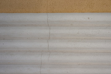 Graue Wand mit rauen Wellen und Rissen in der Wand