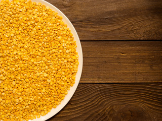 Dry peas in a plate, standing on a wooden table.