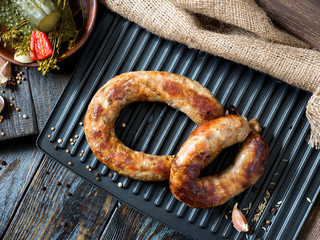 Spicy homemade sausages pork and beef sausages grilled with sauce,  spices and pickled cucumber . Template in rustic style.