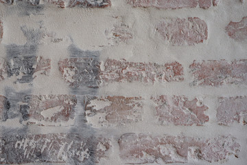 Verputztes Mauerwerk aus Ziegelsteinen mit grauen Fugen