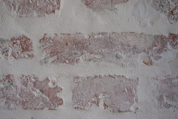 Verputztes Mauerwerk aus Ziegelsteinen mit grauen Fugen