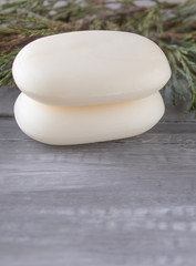 Closeup of white soap on a wooden table with green branches.