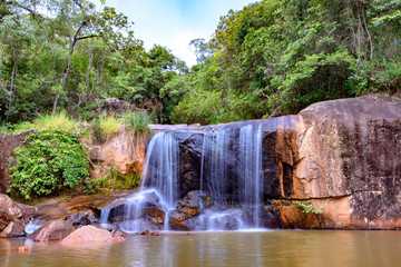 Fototapeta na wymiar Waterfall in rain forest of Moeda in Minas Gerais state on cloudy day among rocks and vegetation
