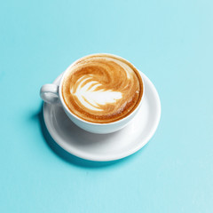 A cup of cappuccino coffee on a blue background