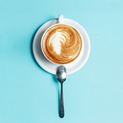 A cup of cappuccino coffee on a blue background
