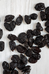 Dry prunes on a white wooden surface, top view. Flat lay, from above, overhead.