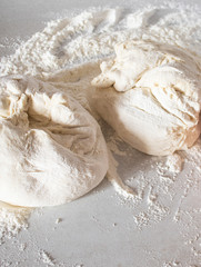 Dough on a white table with flour.