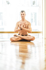 A man who do yoga on the wooden floor